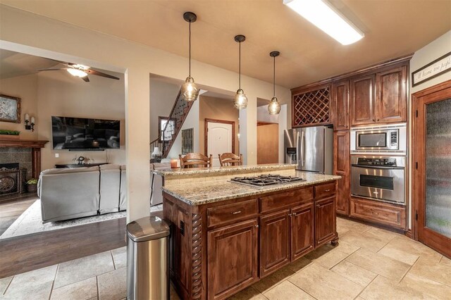 4417 Man O War Dr, Edmond, OK 73025 - kitchen featuring stainless steel appliances, hanging light fixtures, light stone counters, ceiling fan, and a kitchen island