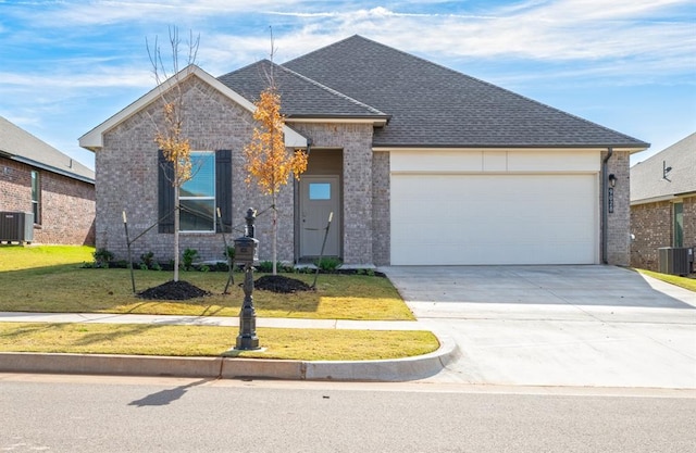 2832 Casey Dr, Yukon, OK 73099 - view of front facade with brick siding, an attached garage, concrete driveway, a front yard, and roof with shingles