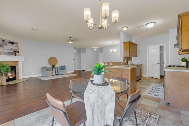 16117 Sonoma Lake Blvd, Edmond, OK 73013 - dining space featuring a chandelier, ceiling fan, a tiled fireplace, and light tile patterned floors