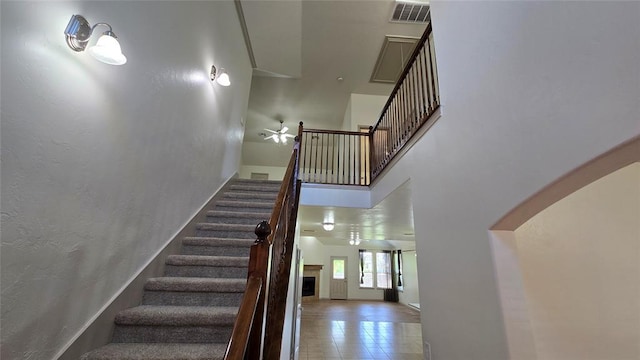3441 NW 176th St, Edmond, OK 73012 - staircase with a high ceiling, ceiling fan, a fireplace, and arched walkways