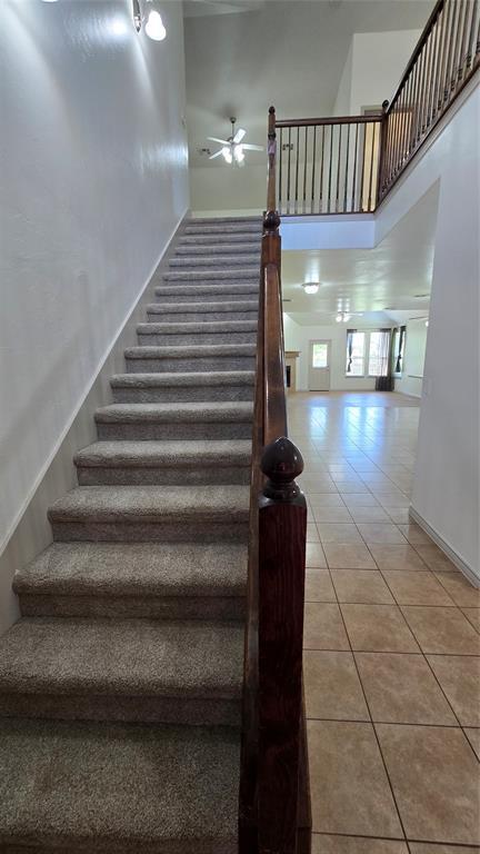 3441 NW 176th St, Edmond, OK 73012 - staircase featuring tile patterned floors, a ceiling fan, and a towering ceiling