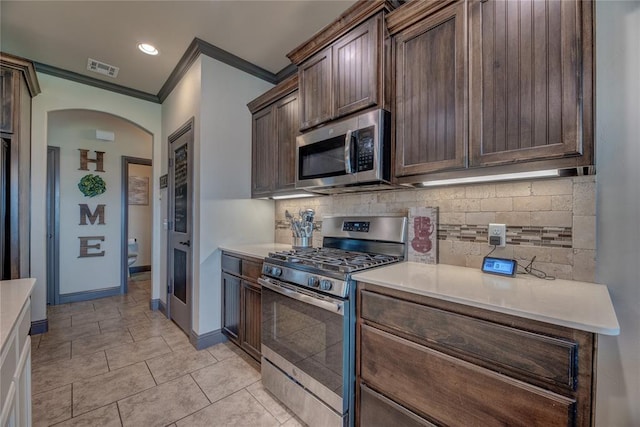 11620 Mallorca Dr, Oklahoma City, OK 73173 - kitchen featuring stainless steel appliances, ornamental molding, arched walkways, decorative backsplash, and light countertops