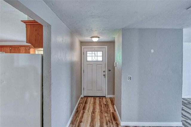 1540 Bradley Pl, Oklahoma City, OK 73127 - doorway featuring a textured wall, light wood-type flooring, and a textured ceiling