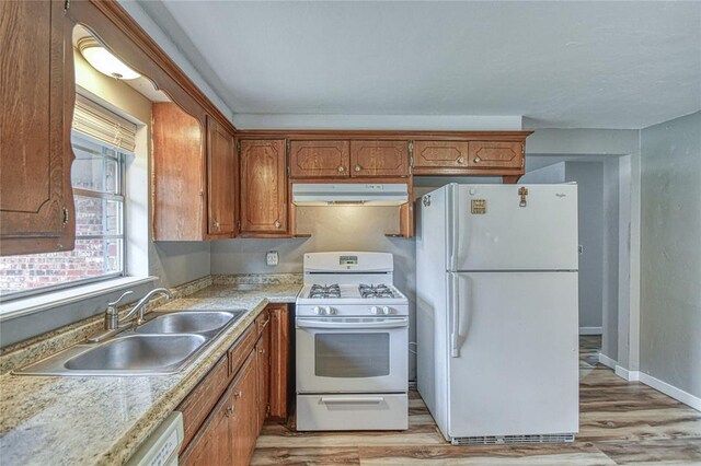 1540 Bradley Pl, Oklahoma City, OK 73127 - kitchen with white appliances, under cabinet range hood, light wood-type flooring, brown cabinets, and light countertops