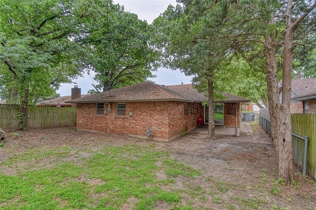 1540 Bradley Pl, Oklahoma City, OK 73127 - rear view of house with a chimney, a fenced backyard, brick siding, and a shingled roof