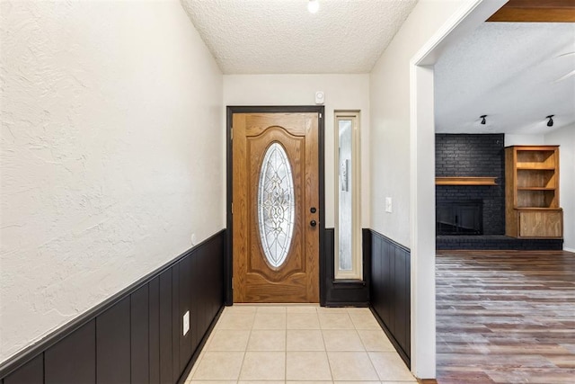 2309 Morning Glory Dr, Oklahoma City, OK 73159 - entryway featuring a textured ceiling, a brick fireplace, and wainscoting