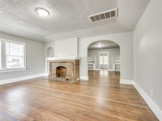 1527 NW 43rd St, Oklahoma City, OK 73118 - unfurnished living room with a textured ceiling, arched walkways, wood finished floors, and a tile fireplace