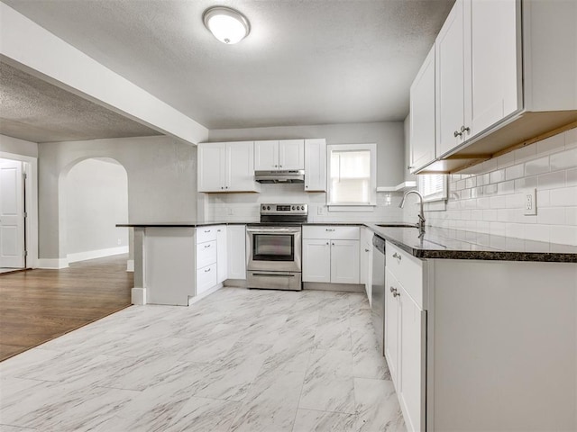 1527 NW 43rd St, Oklahoma City, OK 73118 - kitchen featuring appliances with stainless steel finishes, under cabinet range hood, arched walkways, a textured ceiling, and white cabinets