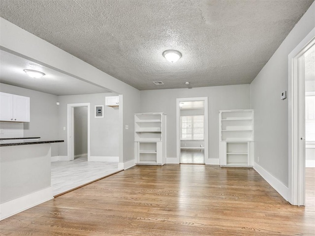 1527 NW 43rd St, Oklahoma City, OK 73118 - unfurnished living room featuring light wood-style floors, a textured ceiling, and built in features