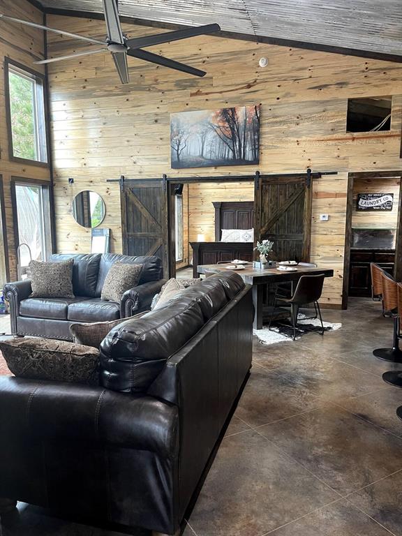17 Honor Ct, Broken Bow, OK 74728 - living area with wood walls, a barn door, vaulted ceiling, and concrete floors