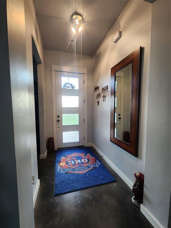 26784 Stirrup Ct, Blanchard, OK 73010 - doorway featuring unfinished concrete flooring and baseboards