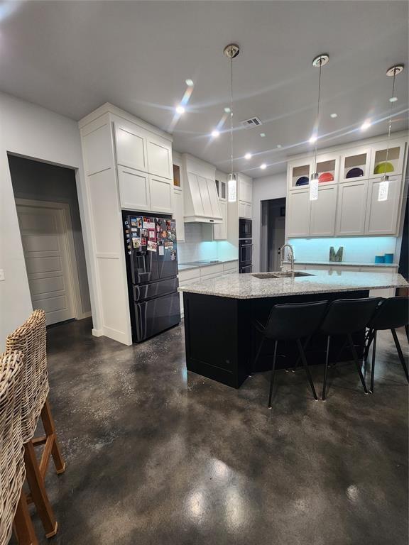 26784 Stirrup Ct, Blanchard, OK 73010 - kitchen featuring black appliances, premium range hood, finished concrete floors, white cabinets, and light stone counters