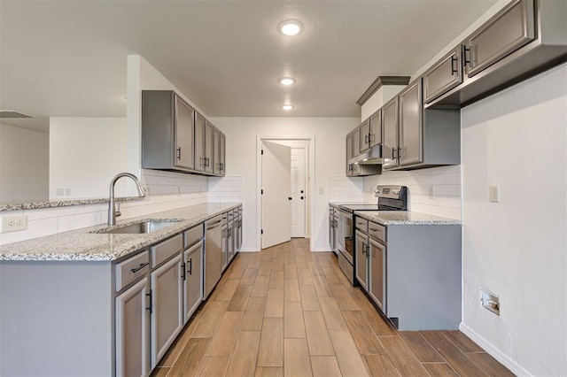 11116 SW 37th St, Mustang, OK 73064 - kitchen featuring appliances with stainless steel finishes, under cabinet range hood, tasteful backsplash, light stone counters, and recessed lighting