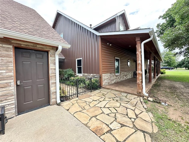 17701 S Rock Creek Rd, Shawnee, OK 74801 - view of exterior entry with stone siding, board and batten siding, roof with shingles, and a patio
