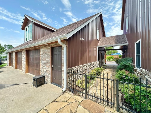17701 S Rock Creek Rd, Shawnee, OK 74801 - view of side of property featuring stone siding, roof with shingles, a garage, driveway, and board and batten siding
