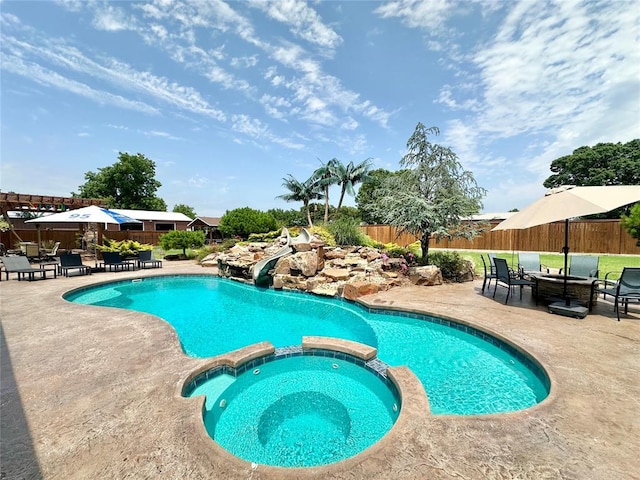 17701 S Rock Creek Rd, Shawnee, OK 74801 - view of swimming pool featuring a water slide, a patio area, a pool with connected hot tub, and a fenced backyard