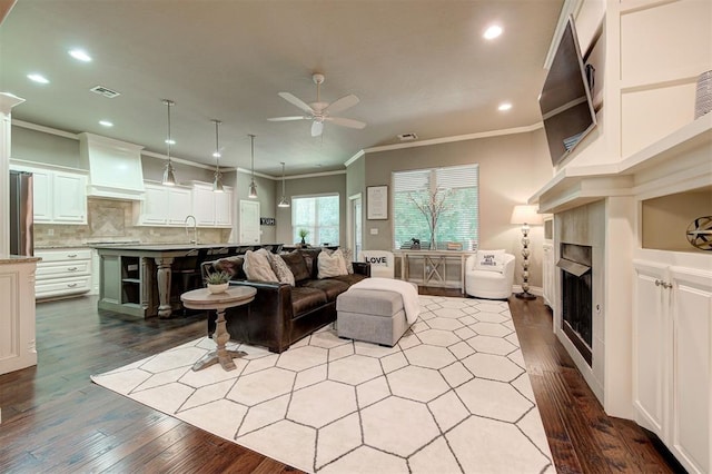 2473 Vellano Ln, Edmond, OK 73034 - living room featuring a ceiling fan, ornamental molding, dark wood finished floors, a fireplace, and recessed lighting