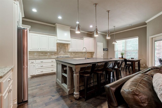 2473 Vellano Ln, Edmond, OK 73034 - kitchen with high end fridge, a kitchen bar, backsplash, dark wood finished floors, and ornamental molding
