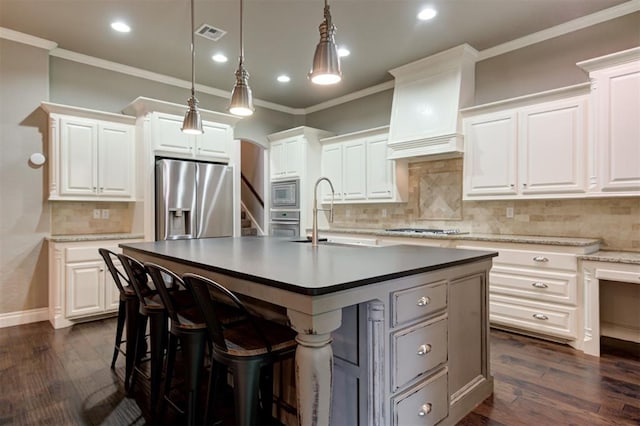 2473 Vellano Ln, Edmond, OK 73034 - kitchen featuring appliances with stainless steel finishes, decorative backsplash, a kitchen island with sink, recessed lighting, and ornamental molding