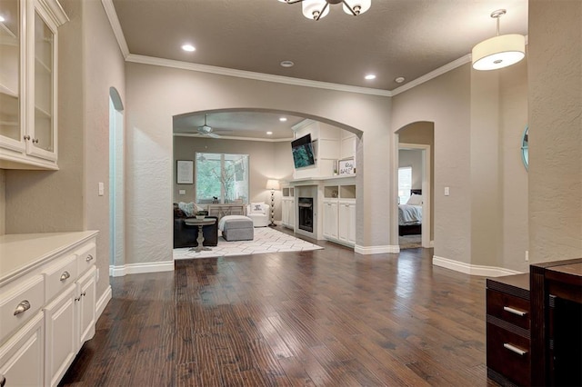 2473 Vellano Ln, Edmond, OK 73034 - unfurnished living room with arched walkways, ornamental molding, dark wood-type flooring, a ceiling fan, and a textured wall