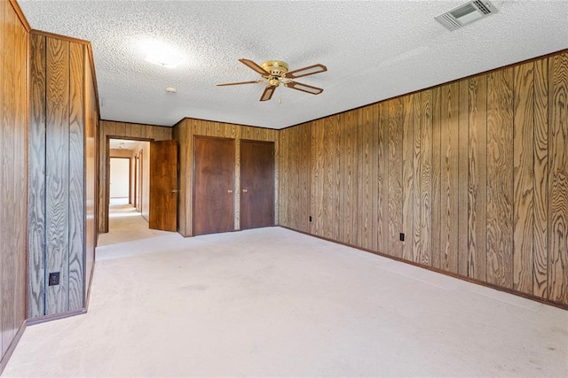 1317 Sue Ln, Choctaw, OK 73020 - unfurnished bedroom with wooden walls, a textured ceiling, light carpet, and a ceiling fan