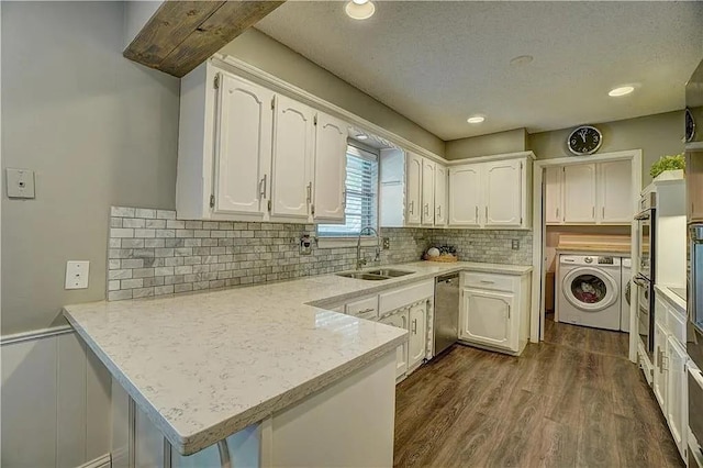 1013 Mary Lee Ln, Edmond, OK 73034 - kitchen featuring a peninsula, dishwasher, white cabinetry, washing machine and clothes dryer, and a wainscoted wall
