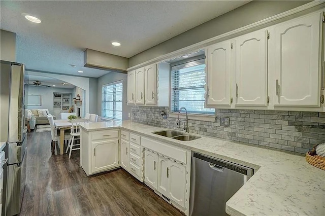 1013 Mary Lee Ln, Edmond, OK 73034 - kitchen featuring stainless steel appliances, a peninsula, white cabinets, dark wood-style floors, and backsplash