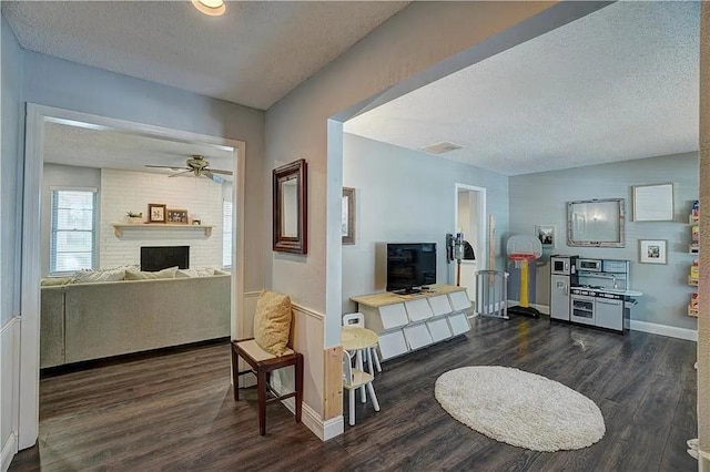 1013 Mary Lee Ln, Edmond, OK 73034 - living room featuring a textured ceiling, wood finished floors, a ceiling fan, and a brick fireplace