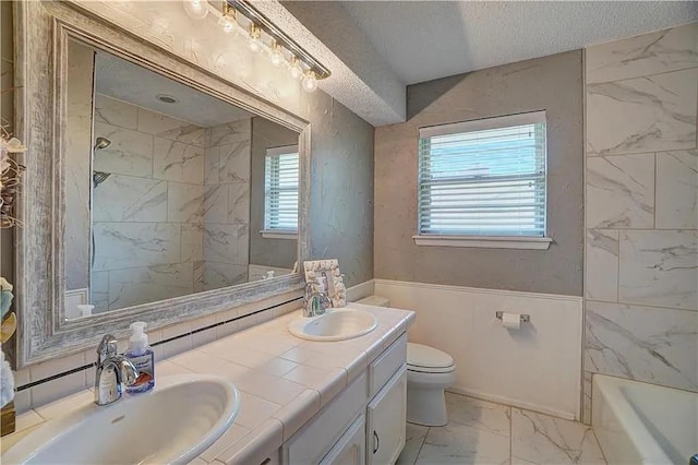 1013 Mary Lee Ln, Edmond, OK 73034 - bathroom featuring marble finish floors, double vanity, a textured ceiling, and a wainscoted wall