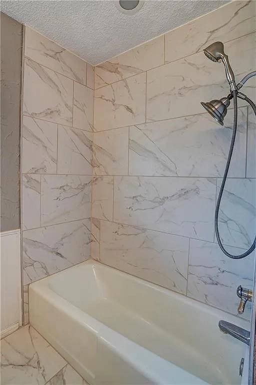 1013 Mary Lee Ln, Edmond, OK 73034 - bathroom with a textured ceiling, marble finish flooring, and bathtub / shower combination