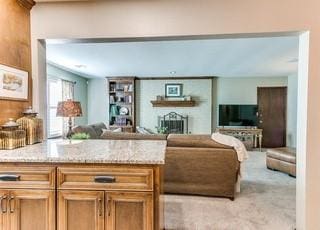 801 Belle Air Ave, Edmond, OK 73013 - kitchen featuring open floor plan, light stone counters, a peninsula, light carpet, and brown cabinetry