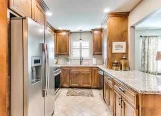 801 Belle Air Ave, Edmond, OK 73013 - kitchen featuring appliances with stainless steel finishes, brown cabinets, a peninsula, and recessed lighting