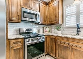 801 Belle Air Ave, Edmond, OK 73013 - kitchen featuring stainless steel appliances, tasteful backsplash, light stone countertops, and brown cabinets