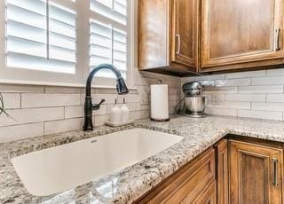 801 Belle Air Ave, Edmond, OK 73013 - kitchen view of brown cabinetry, decorative backsplash, and light stone counters