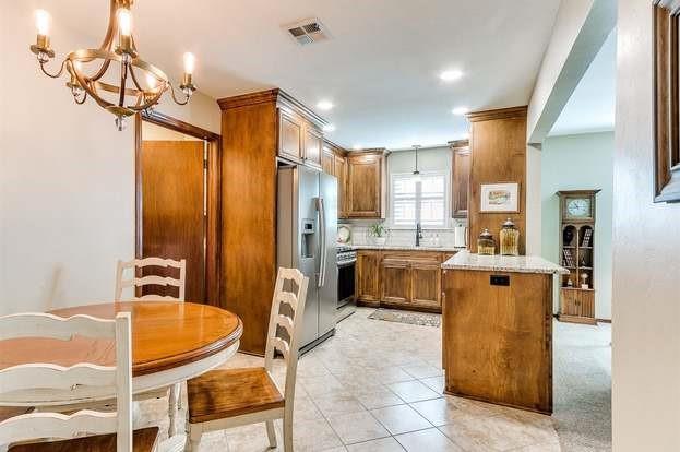 801 Belle Air Ave, Edmond, OK 73013 - kitchen with stainless steel appliances, light countertops, brown cabinetry, a chandelier, and pendant lighting