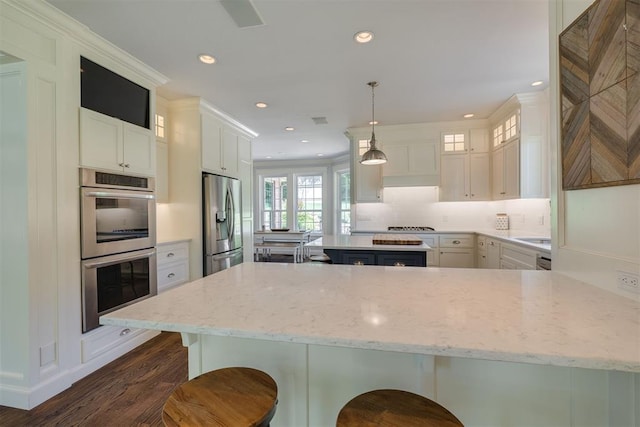 1300 Oak Springs Ln, Edmond, OK 73034 - kitchen with appliances with stainless steel finishes, dark wood finished floors, a kitchen bar, light stone countertops, and a peninsula