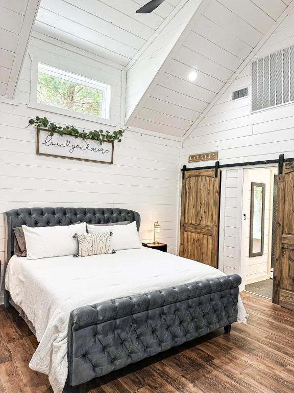142 Champion Way, Broken Bow, OK 74728 - bedroom with a barn door, wood walls, wood finished floors, and lofted ceiling