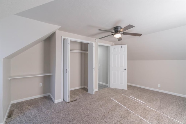 unfurnished bedroom with carpet, a closet, vaulted ceiling, and ceiling fan