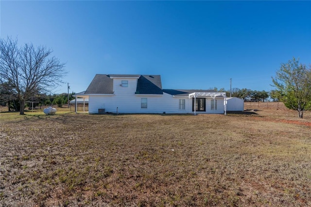 back of house with a lawn and a storage shed