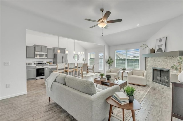 1108 Blackjack Creek Dr, Yukon, OK 73099 - living room featuring lofted ceiling, light wood-style flooring, a ceiling fan, a fireplace, and a chandelier