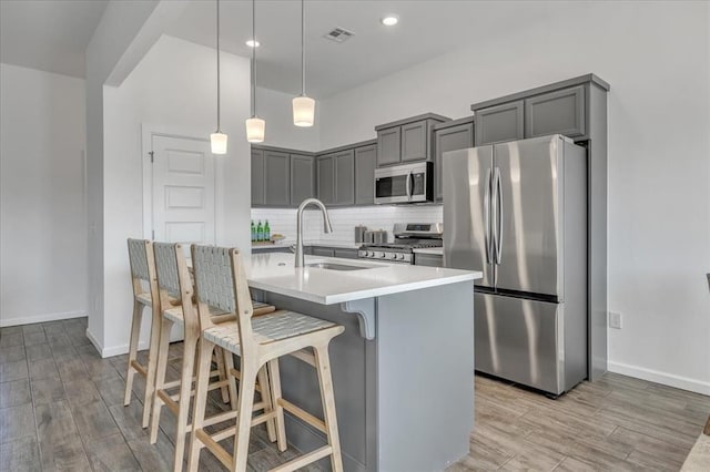 1108 Blackjack Creek Dr, Yukon, OK 73099 - kitchen with stainless steel appliances, gray cabinets, light wood-type flooring, a breakfast bar area, and light countertops