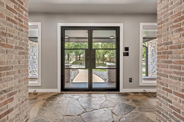 1205 Shalamar Rd, Edmond, OK 73013 - entryway featuring stone floors, brick wall, and french doors