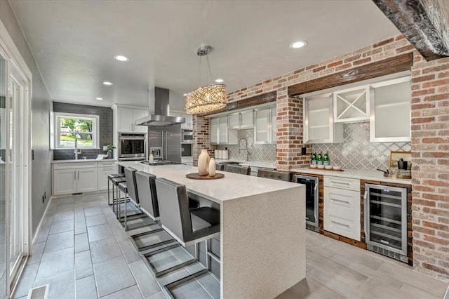 1205 Shalamar Rd, Edmond, OK 73013 - kitchen featuring beverage cooler, wall chimney range hood, backsplash, stainless steel appliances, and recessed lighting