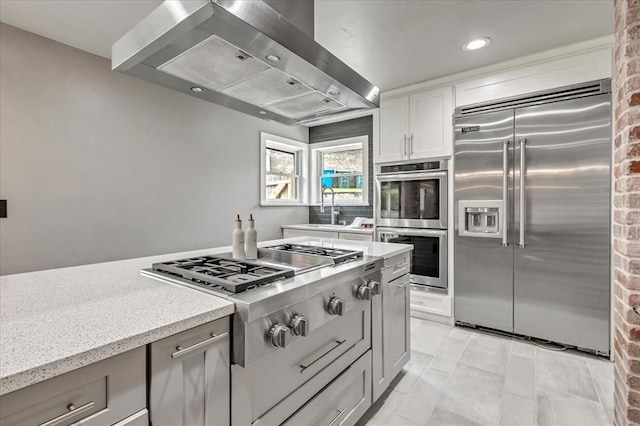 1205 Shalamar Rd, Edmond, OK 73013 - kitchen with stainless steel appliances, wall chimney exhaust hood, gray cabinetry, light stone countertops, and recessed lighting