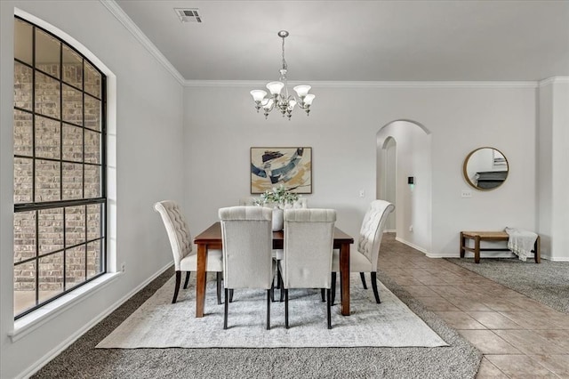732 Tuscany Way, Edmond, OK 73034 - carpeted dining space featuring ornamental molding, a chandelier, arched walkways, and tile patterned flooring