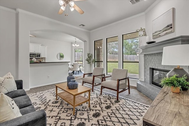 732 Tuscany Way, Edmond, OK 73034 - living area with arched walkways, ornamental molding, a ceiling fan, light carpet, and a fireplace