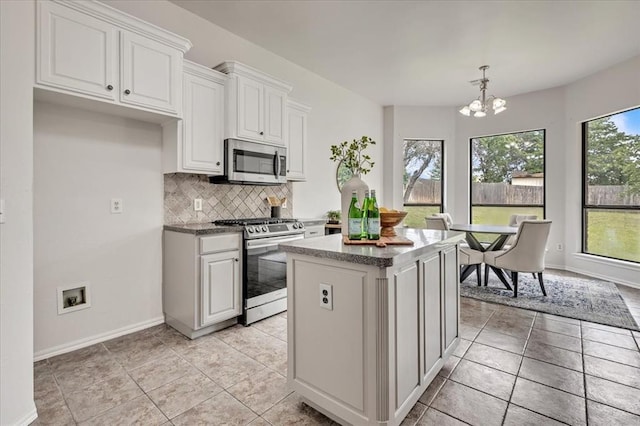 732 Tuscany Way, Edmond, OK 73034 - kitchen featuring appliances with stainless steel finishes, a chandelier, backsplash, a center island, and white cabinetry