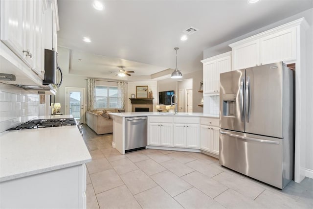 609 NW 180th St, Edmond, OK 73012 - kitchen with stainless steel appliances, open floor plan, ceiling fan, a peninsula, and white cabinets