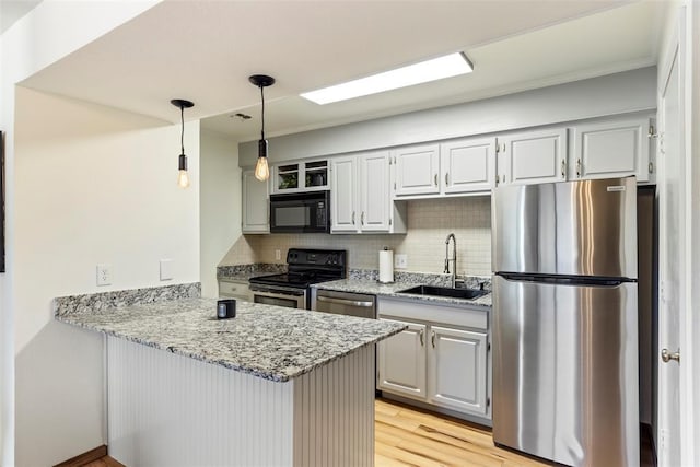 14405 N Pennsylvania Ave Unit 6D, Oklahoma City, OK 73134 - kitchen featuring appliances with stainless steel finishes, a peninsula, backsplash, light stone counters, and light wood-style flooring