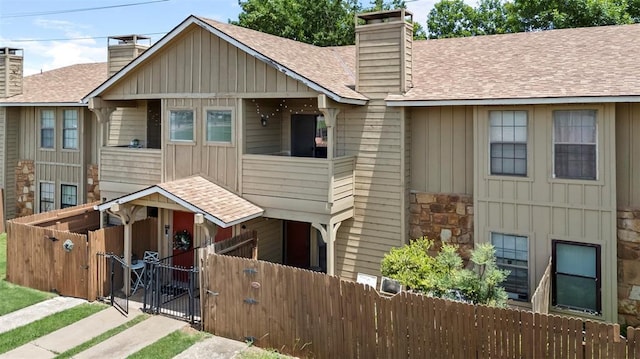 14405 N Pennsylvania Ave Unit 6D, Oklahoma City, OK 73134 - view of front of house with board and batten siding, a gate, a chimney, and roof with shingles